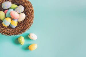 a basket of colored eggs sitting on a light blue background.